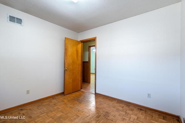 empty room with a textured ceiling and light parquet floors