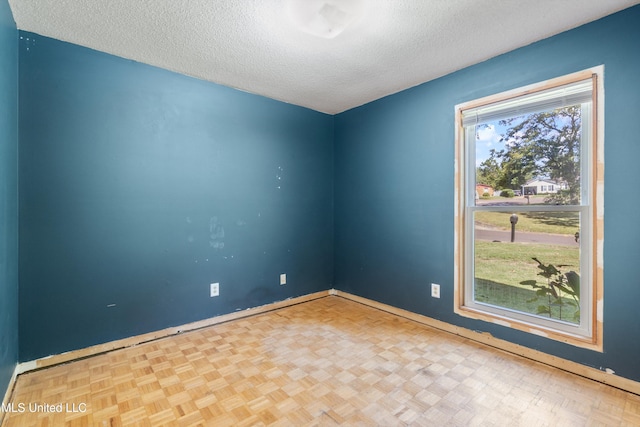 empty room with a textured ceiling and light parquet flooring