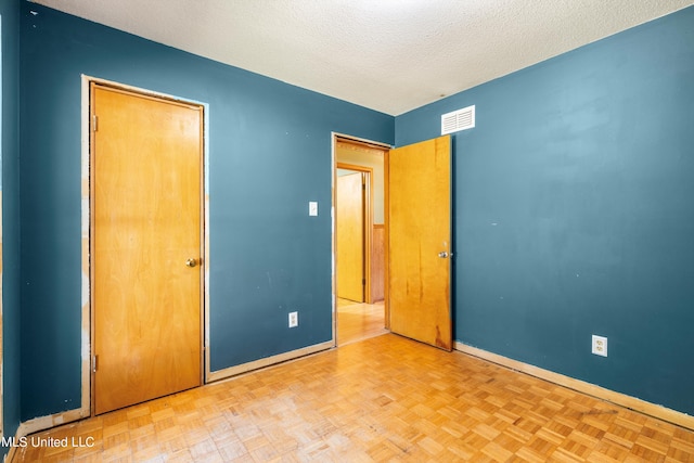 unfurnished bedroom with a textured ceiling and light parquet flooring