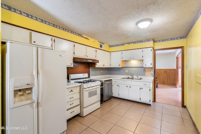 kitchen featuring white appliances, wood walls, sink, a textured ceiling, and white cabinetry