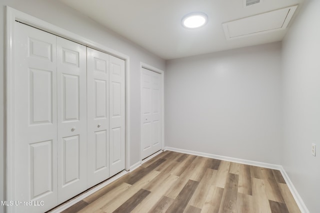 12082 Marlane Pl, Gulfport, MS 39503 - unfurnished bedroom with baseboards, multiple closets, light wood-style floors, and attic access