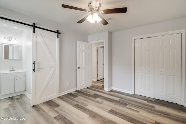 12082 Marlane Pl, Gulfport, MS 39503 - unfurnished bedroom with light wood-type flooring, baseboards, a sink, a barn door, and visible vents