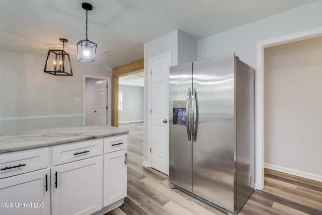 12082 Marlane Pl, Gulfport, MS 39503 - kitchen featuring white cabinets, light wood-style flooring, light countertops, stainless steel refrigerator with ice dispenser, and pendant lighting