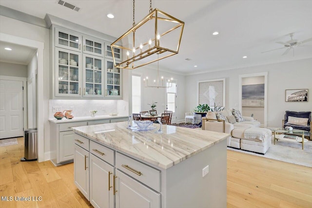 122 Seymour Dr, Madison, MS 39110 - kitchen with a center island, ornamental molding, open floor plan, light wood-style flooring, and a chandelier