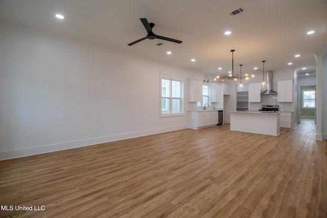 103 E 2nd St, Pass Christian, MS 39571 - unfurnished living room featuring plenty of natural light, light wood finished floors, visible vents, and ceiling fan with notable chandelier