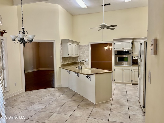 3057 Windwood Cir, Flowood, MS 39232 - kitchen featuring stainless steel oven, a chandelier, high vaulted ceiling, a peninsula, and light tile patterned flooring