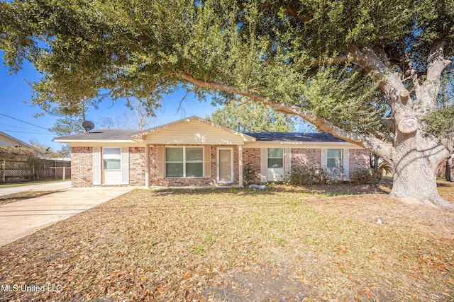 ranch-style home with a front yard, brick siding, and fence