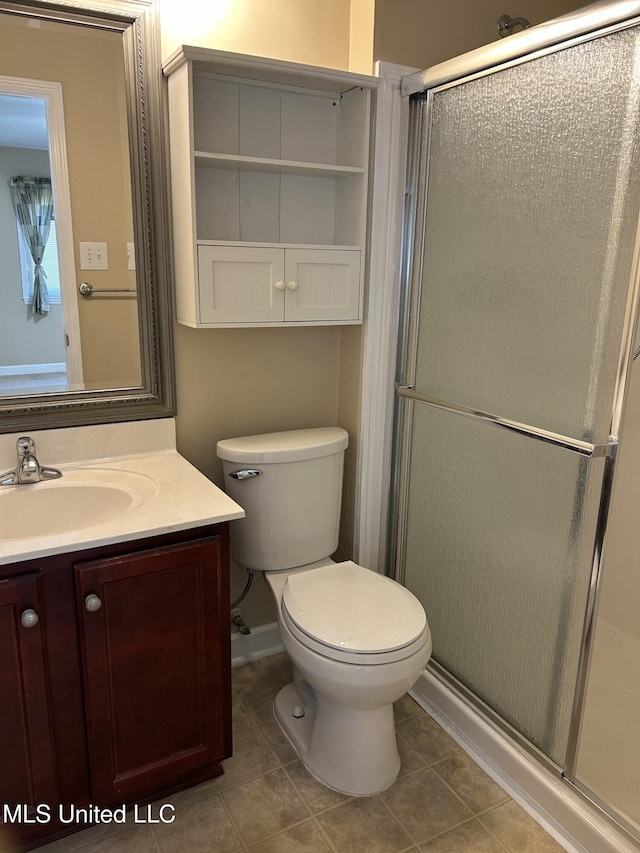 bathroom with tile patterned flooring, a shower with shower door, vanity, and toilet