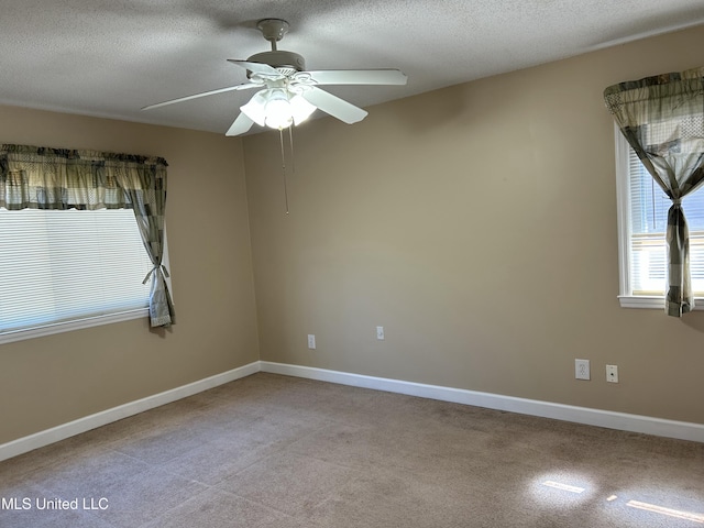 spare room with a ceiling fan, a textured ceiling, and baseboards