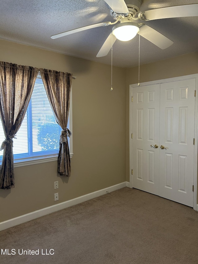 unfurnished bedroom with carpet floors, a closet, a ceiling fan, a textured ceiling, and baseboards