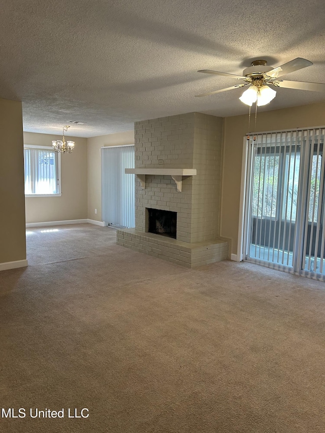 unfurnished living room with a brick fireplace, carpet flooring, baseboards, and ceiling fan with notable chandelier