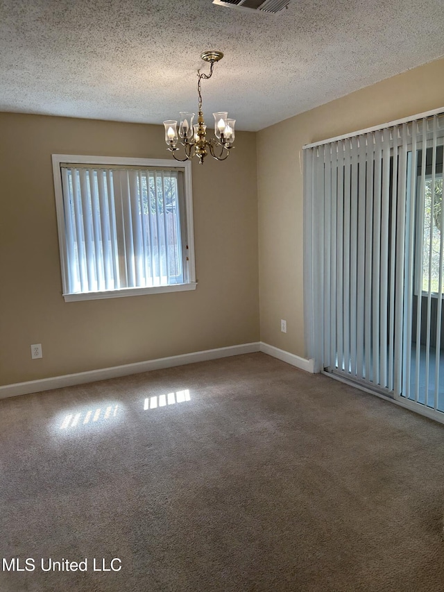 empty room featuring visible vents, baseboards, an inviting chandelier, a textured ceiling, and carpet flooring