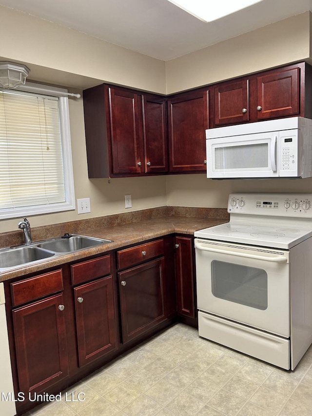 kitchen featuring reddish brown cabinets, white appliances, and a sink