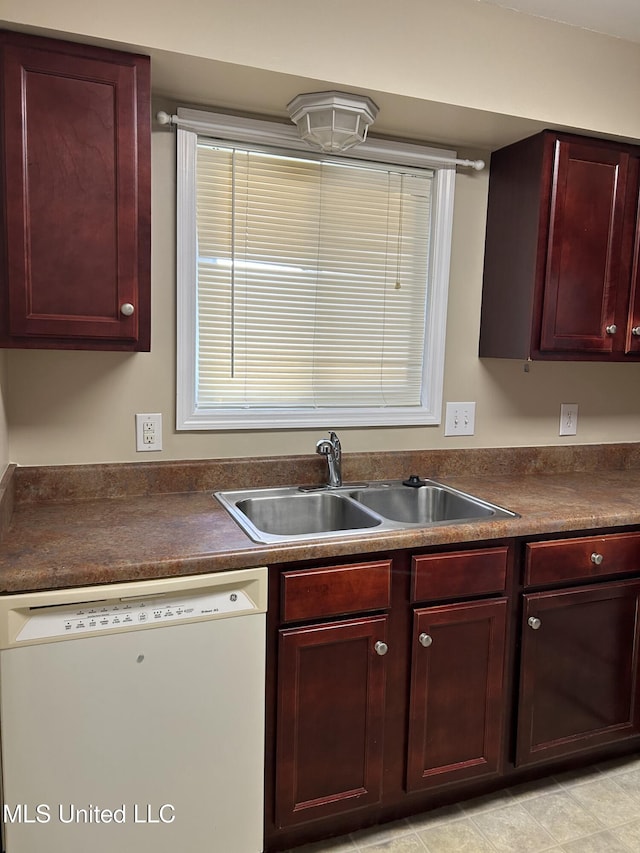 kitchen with dark countertops, dark brown cabinets, white dishwasher, and a sink