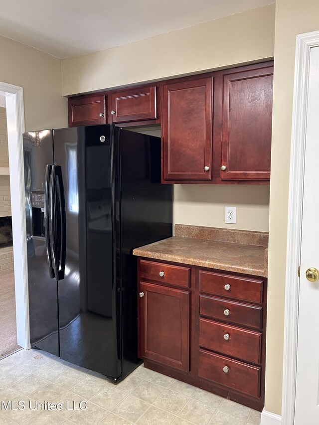 kitchen featuring dark brown cabinets and black fridge