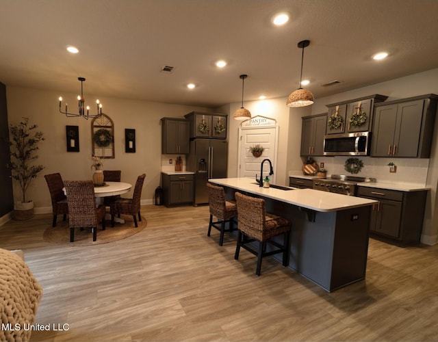 kitchen with high quality appliances, visible vents, a sink, light countertops, and a notable chandelier