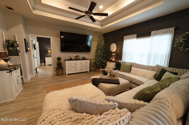 living area with ornamental molding, a ceiling fan, and a tray ceiling