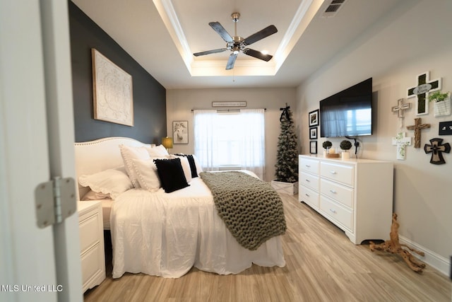 bedroom featuring ceiling fan, light wood finished floors, a raised ceiling, baseboards, and visible vents