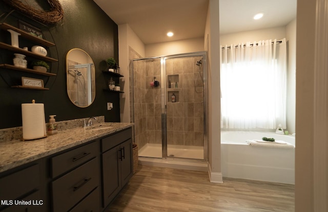 bathroom featuring a garden tub, vanity, wood finished floors, recessed lighting, and a shower stall