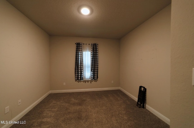 unfurnished room with baseboards, a textured ceiling, and dark carpet