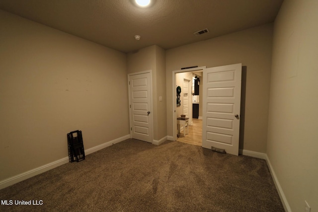 unfurnished bedroom featuring dark carpet, baseboards, and visible vents