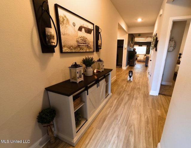 hallway featuring baseboards and light wood-style floors