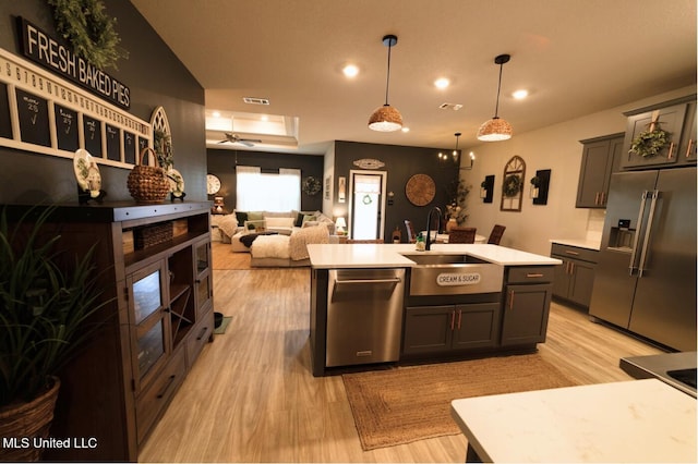 kitchen with a sink, light countertops, light wood-style floors, stainless steel appliances, and recessed lighting