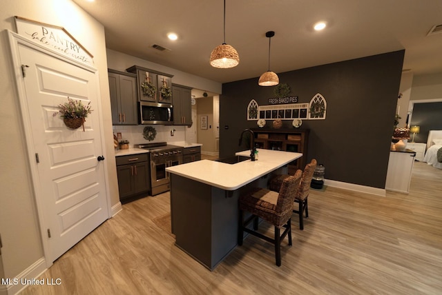 kitchen with visible vents, light wood-type flooring, light countertops, a sink, and appliances with stainless steel finishes