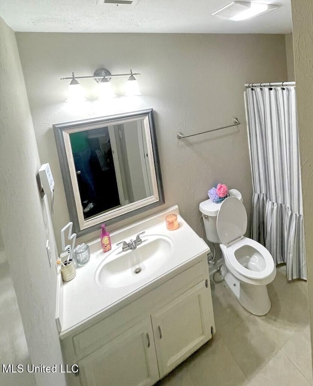 bathroom featuring toilet, vanity, and a shower with curtain