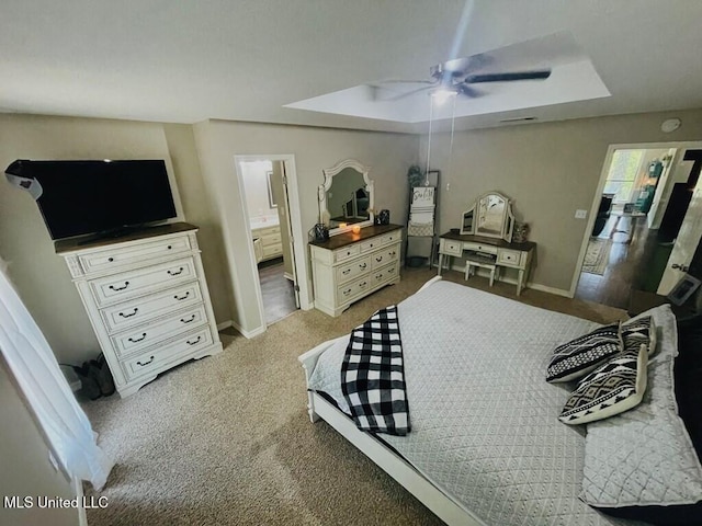 bedroom with ensuite bath, ceiling fan, a tray ceiling, and carpet flooring