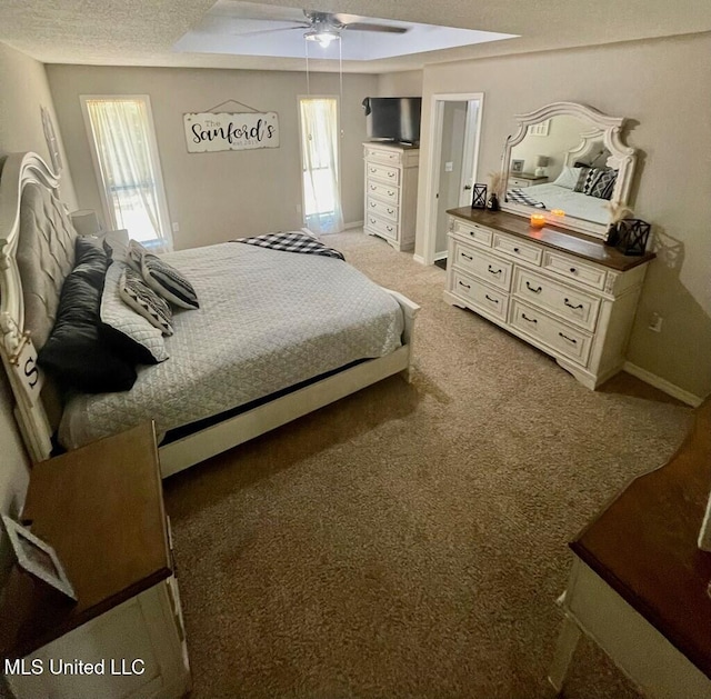 bedroom featuring ceiling fan, multiple windows, a raised ceiling, and carpet floors