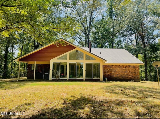 rear view of house featuring a yard and a sunroom