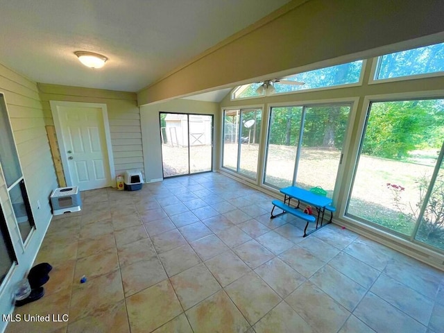 unfurnished sunroom featuring heating unit and vaulted ceiling