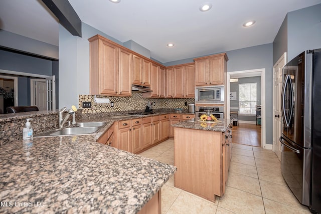 kitchen with sink, light tile patterned floors, stainless steel appliances, a kitchen island, and decorative backsplash