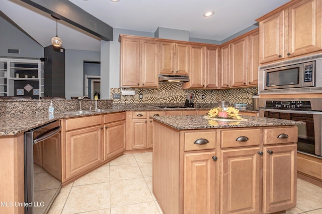 kitchen featuring sink, dark stone countertops, a center island, light tile patterned floors, and stainless steel appliances