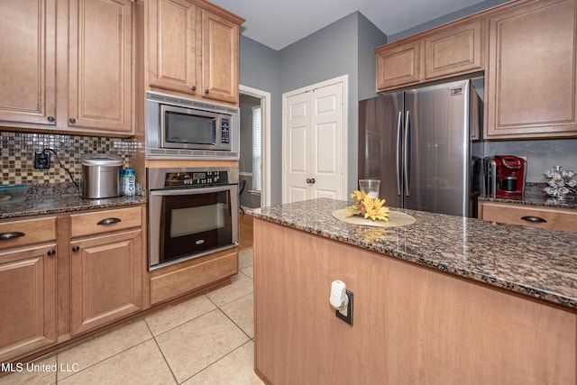 kitchen featuring dark stone countertops, tasteful backsplash, light tile patterned flooring, and appliances with stainless steel finishes