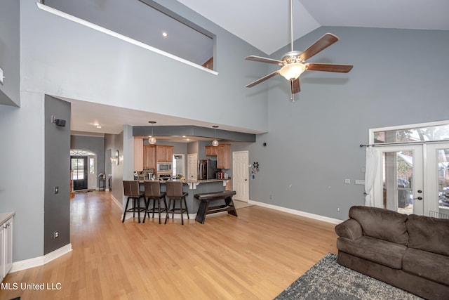 living room featuring french doors, ceiling fan, high vaulted ceiling, and light hardwood / wood-style flooring