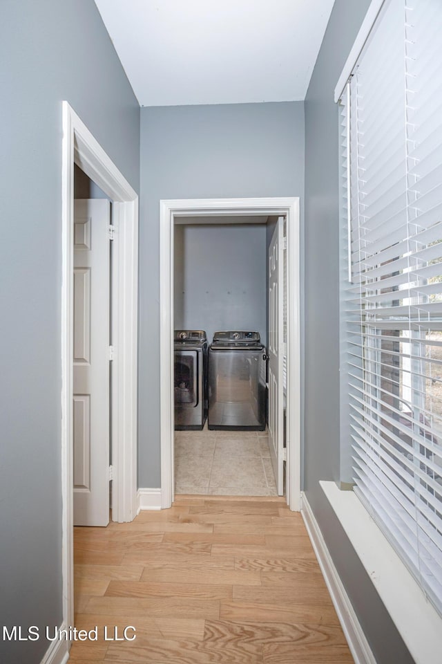 hall with separate washer and dryer and light hardwood / wood-style flooring