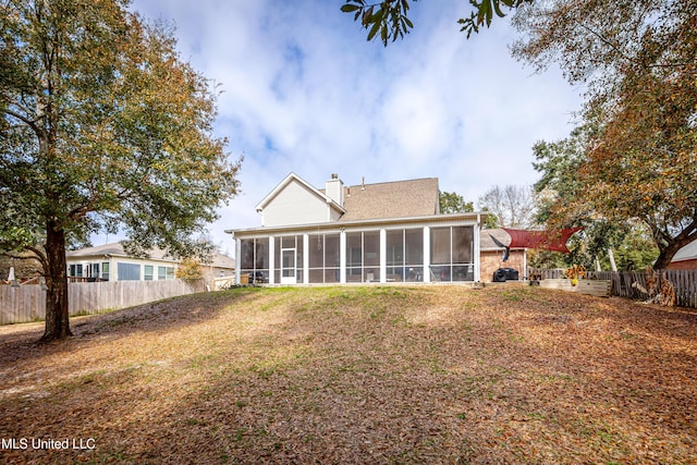 back of house featuring a sunroom and a lawn