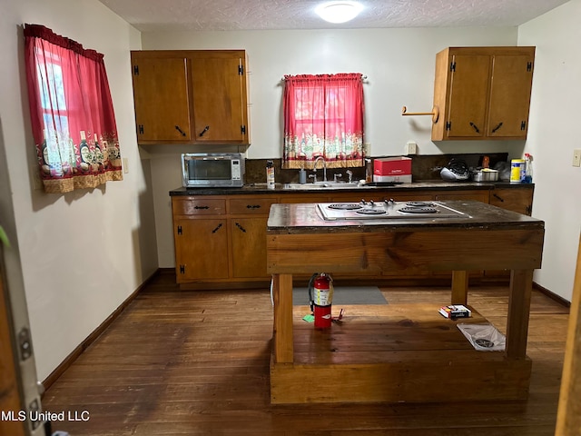 kitchen with a textured ceiling, dark hardwood / wood-style flooring, stainless steel appliances, and sink