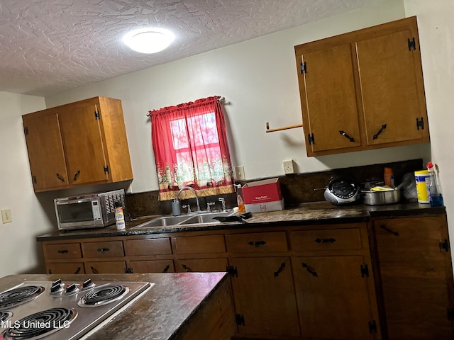 kitchen featuring sink, stainless steel cooktop, and a textured ceiling