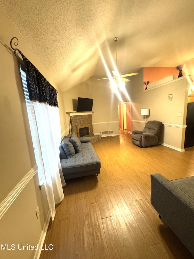 167 Tackett Run, Southaven, MS 38671 - living area with a ceiling fan, a textured ceiling, wood finished floors, vaulted ceiling, and a brick fireplace