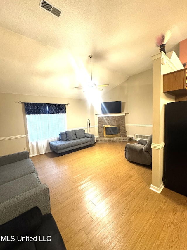 167 Tackett Run, Southaven, MS 38671 - living room with ceiling fan, a textured ceiling, wood finished floors, a brick fireplace, and vaulted ceiling