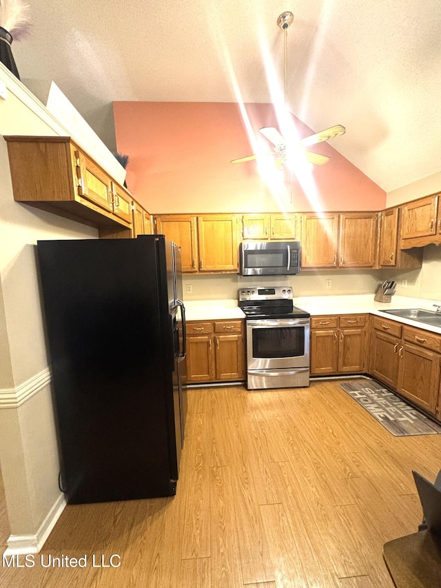167 Tackett Run, Southaven, MS 38671 - kitchen with stainless steel appliances, light wood-style floors, vaulted ceiling, light countertops, and brown cabinetry