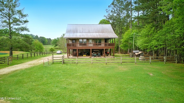 back of property with metal roof, a rural view, and a yard