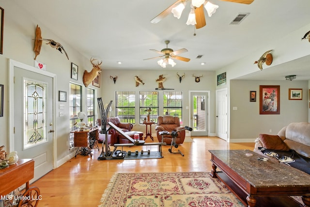 living area featuring baseboards, light wood-style flooring, visible vents, and ceiling fan