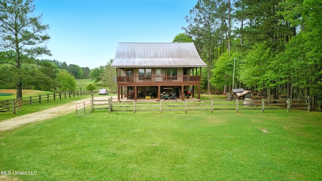 back of house featuring metal roof, a rural view, and a yard