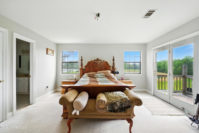 bedroom featuring visible vents, baseboards, access to exterior, ensuite bath, and light colored carpet
