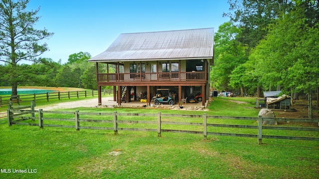 rear view of property featuring a lawn, metal roof, fence, and a wooden deck