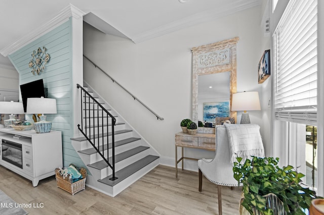 stairs with baseboards, wood finished floors, and crown molding